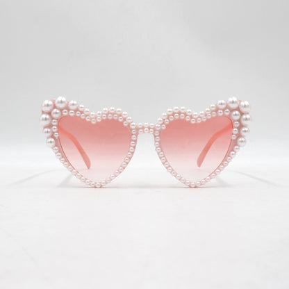 Large frame heart-shaped sunglasses with pearl embellishments, suitable for women to wear during vacations, at the beach, or at birthday parties.