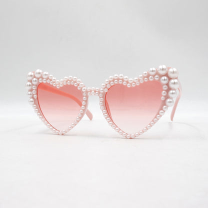 Large frame heart-shaped sunglasses with pearl embellishments, suitable for women to wear during vacations, at the beach, or at birthday parties.